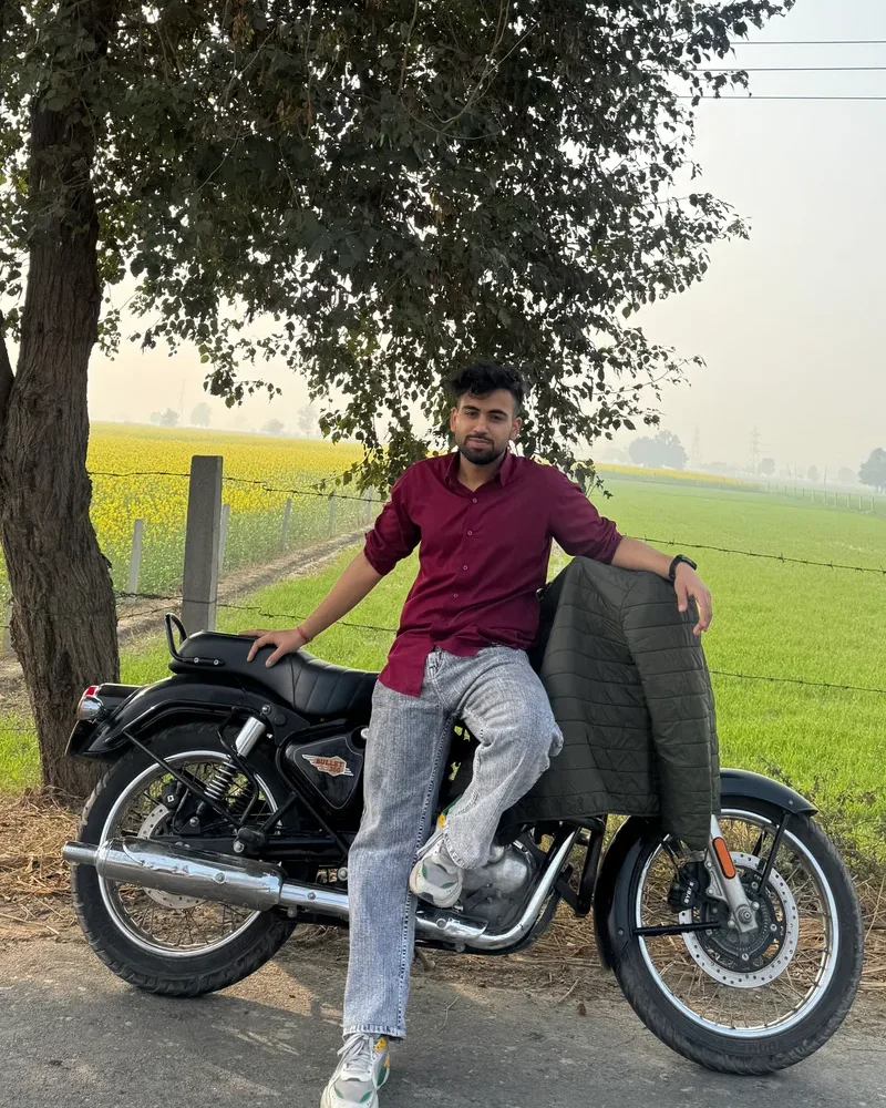 Ujjwal, founder of Shwane Luxe, with his motorcycle in a green field